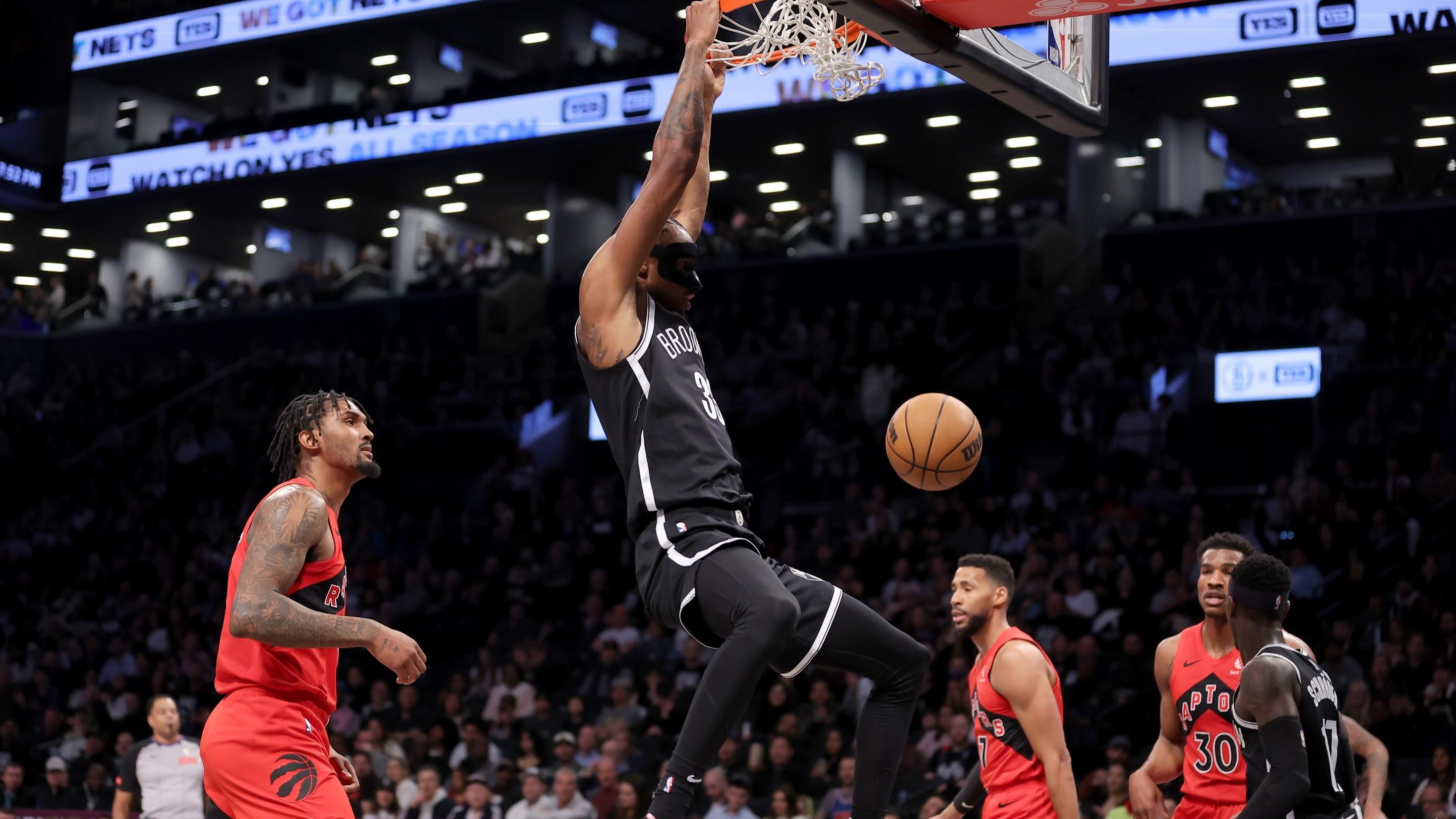 Apr 10, 2024; Brooklyn, New York, USA; Brooklyn Nets center Nic Claxton (33) hangs on the rim after a dunk against Toronto Raptors center Malik Williams (35) and forward Garrett Temple (17) and guard Ochai Agbaji (30) during the first quarter at Barclays Center. / Brad Penner-USA TODAY Sports